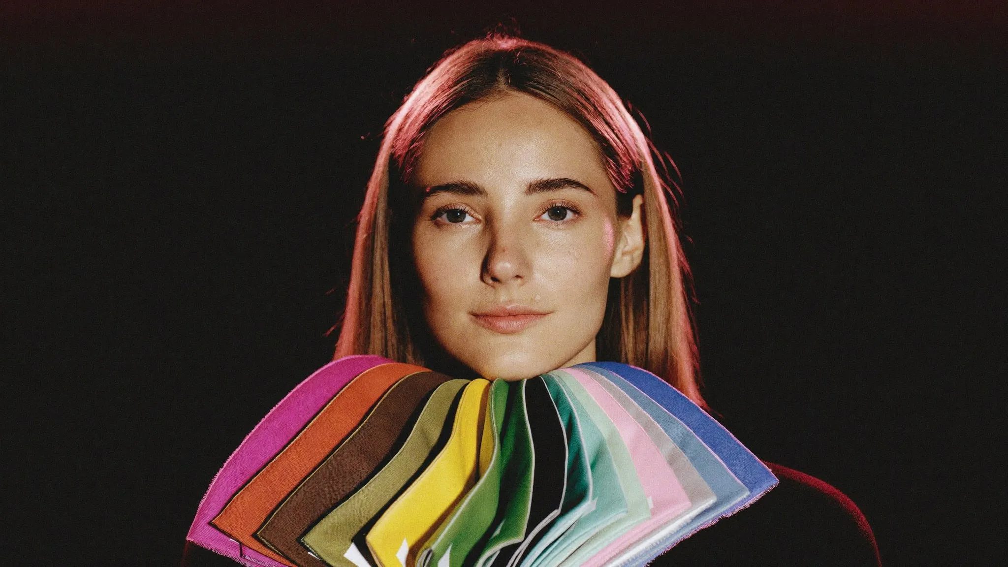 Woman holding warm and cool fabric color swatches fanned below her face during a seasonal color analysis